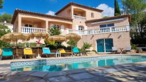 a house with a swimming pool with chairs and umbrellas at Villa Chantilly in Saint-Raphaël