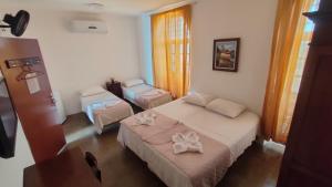 a bedroom with two beds and a table and a window at Pousada Convento da Conceição in Olinda