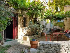 a garden with a red door and a table and chairs at La Maison près de la Fontaine in Saignon