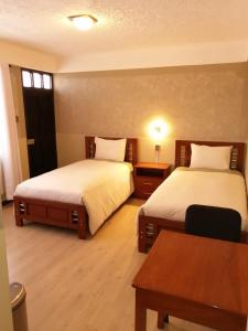 una camera d'albergo con due letti e un tavolo di Hotel CESARE a Uyuni