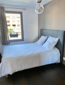 Schlafzimmer mit einem Bett mit weißer Bettwäsche und einem Fenster in der Unterkunft Appart Cosy proche du lac avec terrasse in Annecy