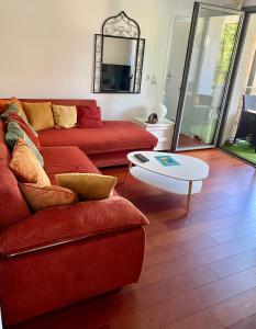ein Wohnzimmer mit einem roten Sofa und einem Tisch in der Unterkunft Appart Cosy proche du lac avec terrasse in Annecy