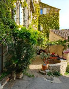 um jardim exterior com uma mesa e árvores e um edifício em La Maison près de la Fontaine em Saignon