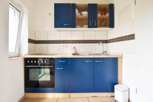 a kitchen with blue cabinets and a sink at Work and Stay Troisdorf in Troisdorf
