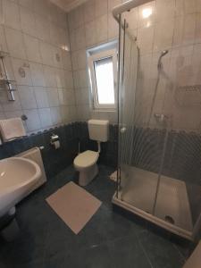 uma casa de banho com um chuveiro, um WC e um lavatório. em Petra Apartmanház em Kehidakustány