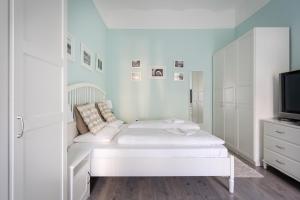 een witte slaapkamer met een bed en een televisie bij Stella Apartment in Boedapest