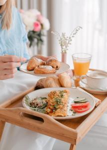 Eine Frau, die an einem Tisch mit zwei Teller Essen sitzt. in der Unterkunft Moje Orłowo Boutique Bed & Breakfast - Adults Only in Gdynia