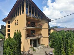 a large yellow building with balconies and tables at Hotel MEITNER in Predeal