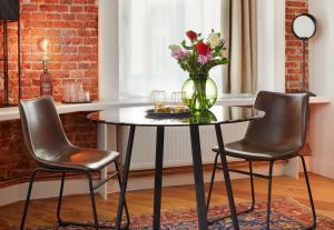 a table with a vase of flowers and two chairs at Aparthotel alsterSuite in Hamburg