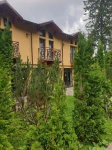 ein gelbes Haus mit Bäumen davor in der Unterkunft Hotel MEITNER in Predeal