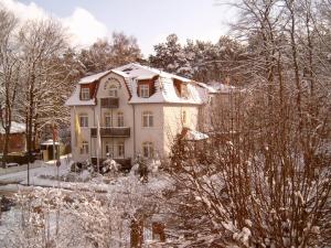 a house covered in snow in a yard at Ringhotel Villa Margarete in Waren