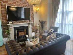 a living room with a leather couch and a fireplace at Beautiful Seaview 2 Bedroom Apartment in Brighton & Hove