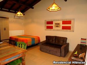 sala de estar con sofá y cama en Residencial Hibiscos - Vista Mar, en Garopaba