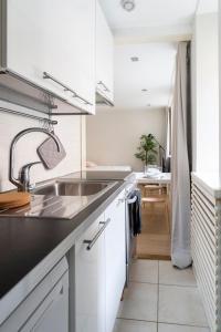 a white kitchen with a sink and a table at 2ndhomes Cozy Studio in the City Center in Helsinki