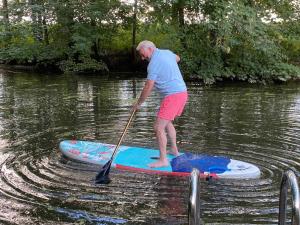 a man standing on a paddle board in the water at Ferienwohnungen Bekperle in Bekdorf