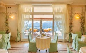 a dining room with a table and chairs and a balcony at Hotel La Perla in Tremezzo