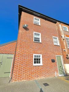 - un grand bâtiment en briques rouges avec des fenêtres et une porte dans l'établissement 75 Weavers Townhouse, à Norwich