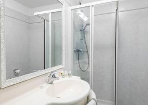 a white bathroom with a sink and a shower at Hotel La Perla in Tremezzo