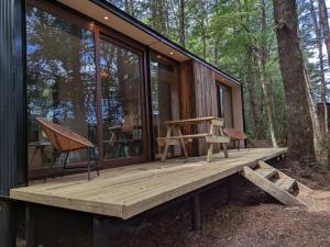 a cabin with a wooden deck in the woods at Refugios Outscape Fuy, Huilo Huilo in Puerto Fuy