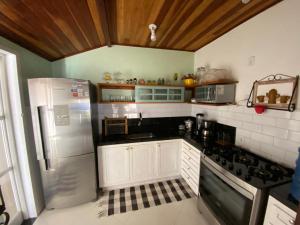 cocina con armarios blancos y nevera en Casa de praia tranquilidade e conforto en Búzios