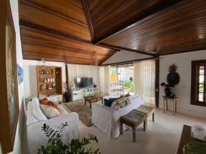 una sala de estar con muebles blancos y techos de madera. en Casa de praia tranquilidade e conforto en Búzios