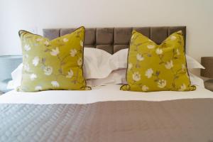Una cama con almohadas amarillas y flores blancas. en Apartment 1 2 bedrooms, sleeps x 6, en York