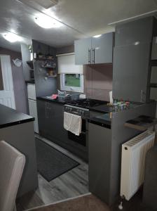 a small kitchen with a stove and a sink at Superb luxury two bed caravan, Todber Valley Holiday Park, sleeps six in Gisburn