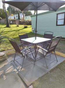 a table and chairs with an umbrella on a patio at Superb luxury two bed caravan, Todber Valley Holiday Park, sleeps six in Gisburn