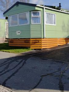 a green caravan parked on the side of a street at Superb luxury two bed caravan, Todber Valley Holiday Park, sleeps six in Gisburn