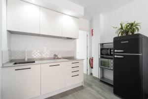 kuchnia z białymi szafkami i czarną lodówką w obiekcie Apartamentos Joya del Mar w mieście Torre del Mar