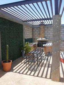een patio met een tafel en stoelen onder een pergola bij HB Alebrijes SC in Lachiraguigú