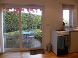 una cucina con porta scorrevole in vetro che conduce a un patio di Oakey Orchard - cosy apartment in Tamar Valley, Cornwall a Saint Dominick