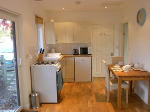 a kitchen with a table and a stove top oven at Oakey Orchard - cosy apartment in Tamar Valley, Cornwall in Saint Dominick
