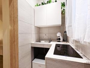 una pequeña cocina con armarios blancos y fregadero en RAVI romantic jacuzzi suite, en Bari