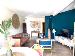 uma sala de estar com um sofá castanho e uma parede azul em T3 moderne au cœur du village em Ouangani