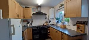 eine Küche mit Holzschränken und einem Backofen mit schwarzem Kochfeld in der Unterkunft Cosy Retreat - house with double bedroom in Ripon