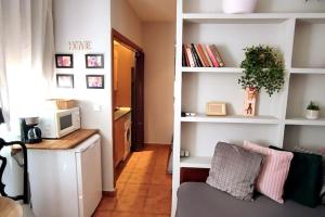 a living room with a couch and a desk with a microwave at Estudio Lavapiés cerca de Antón Martín in Madrid