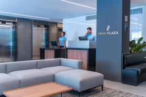 a lobby with a couch and two people at a counter at Park Plaza Moinhos Porto Alegre in Porto Alegre