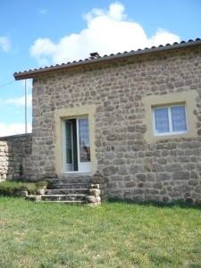 a stone house with two windows and some grass at Gite de la croix in Apinac