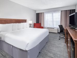 Habitación de hotel con cama blanca grande y escritorio. en Country Inn & Suites by Radisson, Toledo, OH en Maumee