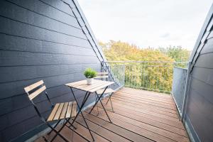 um deque de madeira com uma mesa e cadeiras numa varanda em FULL HOUSE Premium Apartments - Zwickau rooftop em Zwickau