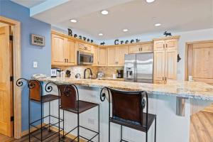 a kitchen with a large island with two bar stools at St James Place by East West Hospitality in Beaver Creek