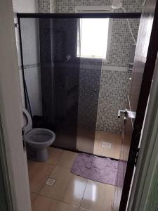 a bathroom with a toilet and a glass shower door at Apto Aconchegante Praia Grande in Praia Grande