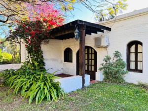 a house with red flowers on the side of it at La Mansa Riverside in Esquina