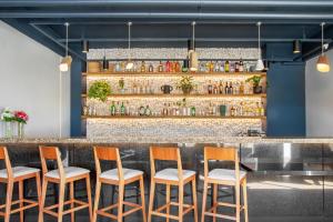 a bar with four chairs in front of a counter at São Paulo Tatuape, Affiliated by Meliá in São Paulo