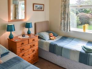 a bedroom with two beds and a dresser with a teddy bear on it at Montana Cottage in Happisburgh