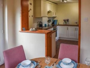 a kitchen with a table and two pink chairs at Montana Cottage in Happisburgh