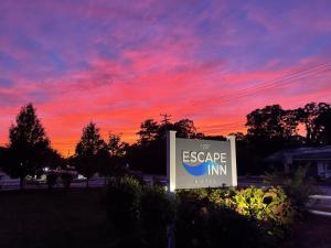 um sinal para uma estalagem de fuga com um pôr-do-sol ao fundo em The Escape Inn em South Yarmouth