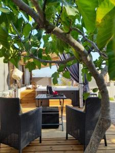 un patio con 2 sillas, una mesa y un árbol en L'antre deux Pierres, suite de charme, romantisme, jacuzzi privé, braséro en Bouyon