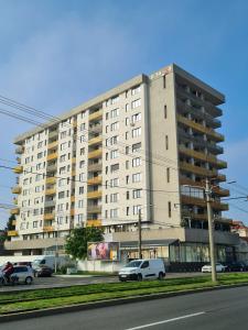 un gran edificio blanco con coches estacionados frente a él en CENTRAL Apartament Urbana, en Arad